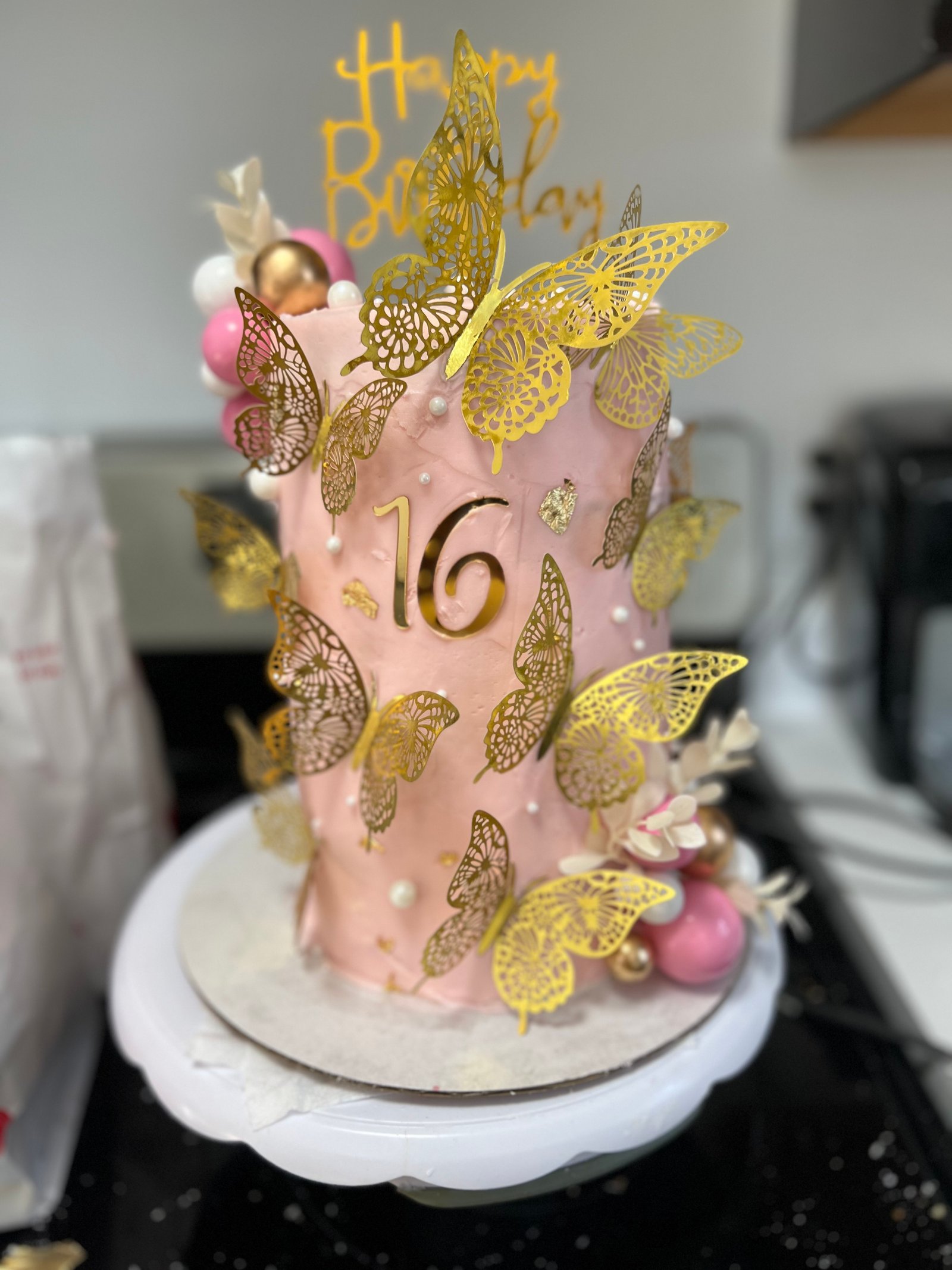 Pink sweet-sixteen birthday cake with gold butterfly decorations